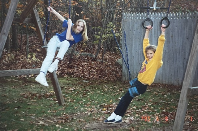 Two girls playing on a backyard swing set and gymnastics rings