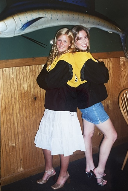 Two friends laughing together in matching varsity jackets